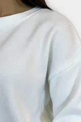 Buzo de tejido de punto en color blanco, con cuello redondo y diseño de corte recto y holgado.