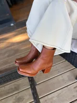 Bota de caña media color óxido, confeccionada en cuero, con plataforma y taco cuadrado texturizado, punta cuadrada y cierre lateral.