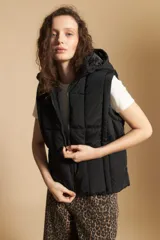 Chaleco acolchado de nylon color negro, con diseño capitoneado, capucha integrada y cierre frontal con tirador metálico.