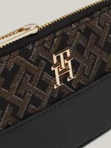Billetera Tommy Hilfiger con estampado integral del monograma TH en jacquard, paneles con mezcla de texturas, diseño estilizado, cierre de cremallera e insignia del monograma TH en la parte delantera.