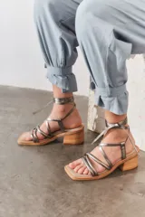 Sandalias de cuero metalizado color plata, con diseño de tiras finas que se atan al tobillo, puntera cuadrada y taco bloque de madera.