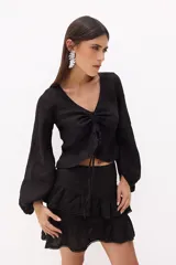 Top corto de lino italiano a rayas verticales beige y blanco, con escote en V, jareta ajustable con lazo en el centro delantero y volado en el ruedo. Mangas largas estilo globo con puños elásticos.