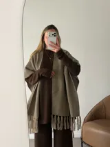 Ruana negra de tejido liviano con terminación de flecos en el ruedo y mangas amplias.