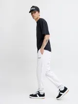 Pantalón de jogging color gris melange, con corte regular y cintura elástica con cordón ajustable. Presenta puños acanalados en los tobillos y un pequeño logo bordado en la parte superior de la pierna izquierda.