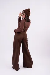 Jean wide-leg color marrón chocolate, con tiro medio, bolsillos frontales y traseros, y costuras decorativas verticales a lo largo de las piernas.