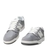 Championes urbanos New Balance modelo 480, color gris con detalles en blanco. Confeccionados en gamuza y malla, presentan el logo N característico en los laterales y suela de goma.