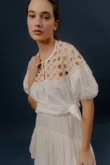 Blusa blanca de algodón con detalles de crochet en la parte superior y mangas cortas abullonadas.