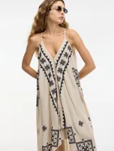 Vestido largo negro con breteles finos y estampado dorado con motivos geométricos. Corte evasé con picos en los laterales.