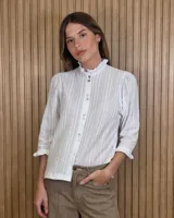 Camisa blanca de algodón con detalles de bordado inglés en rayas verticales, cuello alto con volados y cierre frontal con botones.
