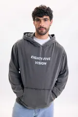 Hoodie de color gris oscuro con efecto lavado, capucha y bolsillo tipo canguro. Presenta una gran estampa en la espalda con la inscripción 'Eighty-Five Vision', una fotografía en blanco y negro de un automóvil clásico y texto descriptivo.