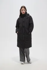 Campera larga tipo parka acolchada color negro, con capucha desmontable, cierre frontal con botones a presión, bolsillos laterales y cordón ajustable en la cintura.