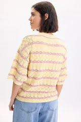 Sweater de punto fantasía color amarillo con líneas horizontales onduladas en color fucsia, de cuello redondo y manga corta.