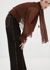 Jeans de corte recto y tiro medio color marrón, con detalles de tachas metálicas en las costuras laterales.