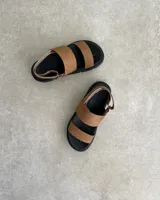 Sandalia negra de plataforma gruesa, con dos tiras anchas sobre el empeine y tira ajustable en el talón.