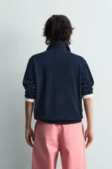 Jersey de punto color azul marino, de corte relajado, con cuello solapa y cierre frontal de tres botones. Presenta mangas largas y acabados en rib en puños y bajo.