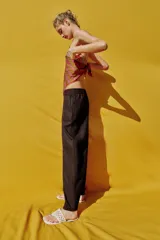 Pantalón de lino marrón oscuro, de corte barrel con pernera holgada que se estrecha hacia el tobillo, cintura elástica y bolsillos delanteros.