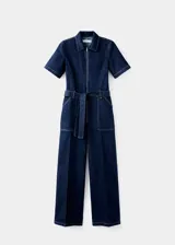 Mono de denim azul oscuro con cierre frontal de cremallera, cuello camisero y mangas cortas. Presenta un corte recto, bolsillos de parche delanteros y traseros, y un cinturón de la misma tela para ajustar la cintura.