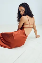 Vestido midi de tejido satinado color terracota, con escote en pico, tirantes finos ajustables y espalda con tiras cruzadas.