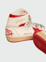Zapatillas de caña alta Golden Goose modelo Sky-Star, confeccionadas en cuero blanco con efecto desgastado. Presentan una estrella roja en el lateral, detalle de talón rojo y suela de goma con acabado envejecido.