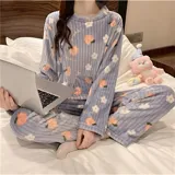 Conjunto de pijama de dos piezas confeccionado en plush suave, compuesto por una remera de manga larga y pantalón largo. Presenta un diseño estampado de duraznos sobre fondo color crema.