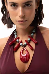 Collar con dije central en forma de gota de acrílico rojo veteado, decorado con bastones de acrílico rojo y cuentas esféricas de cerámica en tonos turquesa y animal print. Se ajusta mediante un tiento regulable.
