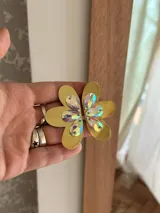 Par de aros dorados con forma de flor y cristales facetados de vidrio de colores. El perno que pasa por la oreja es de acero quirúrgico.