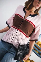 Remera de punto con diseño retro de bloques de color en marrón, crema y celeste. Presenta cierre frontal, cuello redondo, mangas cortas y tejido calado en la parte inferior. Incluye detalle de logo en relieve en el frente.