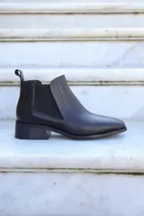 Bota corta de cuero negro con elástico lateral, punta fina y taco bajo.