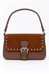 Bolso tipo cartera de mano color marrón, confeccionado en cuerina y gamuza, con solapa frontal decorada con tachas metálicas plateadas y una tira con hebilla central. Cuenta con un asa corta para llevar al hombro.