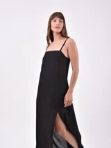 Vestido largo negro de lino con tirantes finos, escote recto y tajo lateral en la falda.