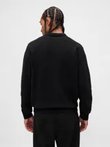 Buzo tipo polo de tejido suave, con cuello clásico, cierre frontal de botones y puños y ruedo acanalados.