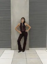 Top estilo nadador con cierre frontal completo, confeccionado en tela con efecto lavado artesanal en tonos rojizos y negros. Presenta un diseño ajustado con costuras visibles y un pequeño logo bordado en el pecho.