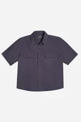 Camisa de manga corta color gris oscuro, corte boxy, con cuello clásico, cierre frontal con botones y dos bolsillos de parche en el pecho.