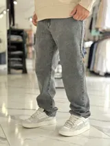 Pantalón de jean gris con efecto deslavado, corte baggy y diseño holgado.