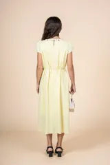 Vestido midi amarillo pálido, de corte recto y manga corta, con escote redondo con detalle de bordado floral. Tiene lazo ajustable en la cintura.