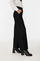 Pantalón negro de tiro alto, corte palazzo y estampado a rayas verticales.