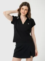 Remera de manga corta con cuello polo y abertura frontal en V. Presenta detalles de rayas blancas en el cuello y un pequeño logo bordado en el pecho.