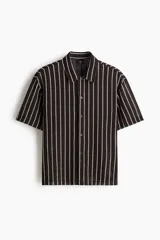 Camisa de manga corta en punto texturizado, de corte estándar, con diseño a rayas verticales en color marrón y blanco, cuello y cierre frontal de botones.