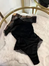 Body negro de terciopelo acanalado con detalles de microtul y encaje, cuello alto y espalda descubierta.