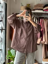 Camisa oversize color marrón con diseño a rayas finas, cuello camisero, manga larga y bolsillo aplicado en el pecho.