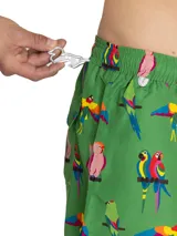 Short de baño de secado rápido con estampado de guacamayos sobre fondo verde. Cuenta con cintura elástica, cordón ajustable, bolsillos laterales y bolsillo trasero.