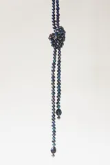 Collar largo de perlas negras de vidrio con diseño anudado en la parte superior y terminaciones con perlas de mayor tamaño.