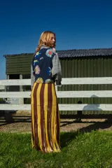 Falda larga tejida a mano con rayas horizontales marrones y amarillas, con flecos en el ruedo.