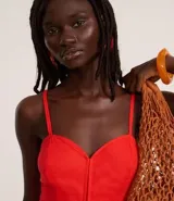 Mono de mujer color rojo, de corte recto y pierna ancha, con breteles finos ajustables y escote corazón. Presenta un detalle fruncido en la espalda (lastex).