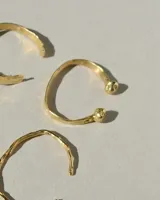 Brazalete rígido abierto de metal color plateado, con terminaciones en forma de herradura.