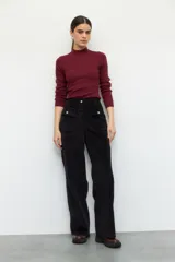 Pantalón de pana color verde oliva, de tiro alto y corte recto. Cuenta con cuatro bolsillos, los delanteros con solapa y botón metálico.