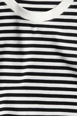 Remera de corte recto en punto suave de algodón con cuello redondo ribeteado y hombros ligeramente caídos. Diseño a rayas horizontales blancas y negras.