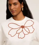 Blusa boxy de mangas cortas color blanco, confeccionada en algodón, con cuello redondo y bordado floral en el frente.