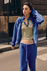 Chaqueta azul de algodón con cuello alto, cierre frontal de cremallera, bolsillos laterales y mangas largas con puños elásticos.