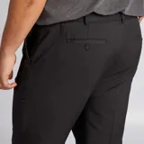 Pantalón de vestir de corte slim en color negro, con cierre frontal y bolsillos laterales. Presenta una línea de planchado marcada a lo largo de la pierna.